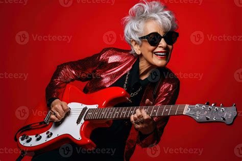 Portrait Of A Cool Trendy Old Woman Playing A Guitar On Red Studio