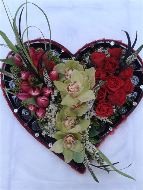 A Heart Shaped Arrangement With Red Flowers And Greenery