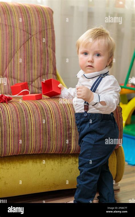 Little Boy Child Stands By The Couch With A Festive T Box In A