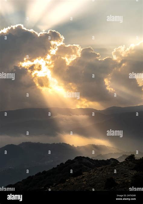 Bright Sun Rays Light Shining Through Dark Clouds Over Mountain At