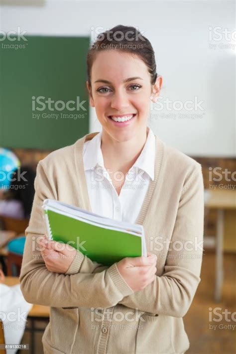 Pretty Teacher Smiling At Camera At Back Of Classroom Stock Photo