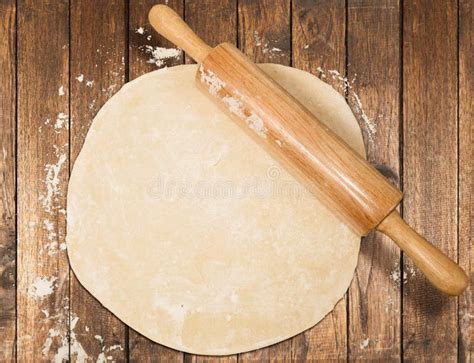 Rolled Dough With Rolling Pin On Wooden Table Covered With Baking Flour