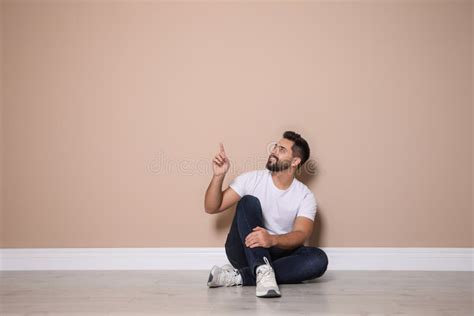 Young Man Sitting On Floor Near Beige Wall Indoors Stock Photo Image