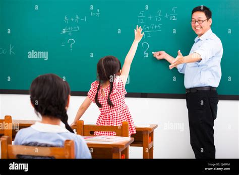 Teacher Asking Question With Children In Classroom Stock Photo Alamy