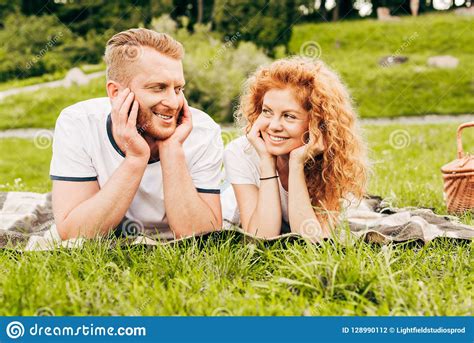 Happy Redhead Couple Smiling Each Other While Lying Together On Plaid