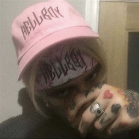 A Person With Tattoos And A Pink Hat Covering Their Face While Taking A