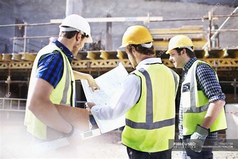 Trabajadores De La Construcción E Ingeniero Revisando Planos En Obra