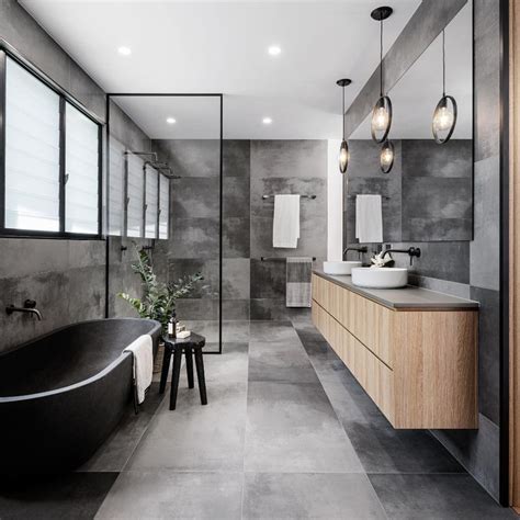 A Modern Bathroom With Grey Walls And Flooring Black Bathtub Large Mirror Two Sinks And