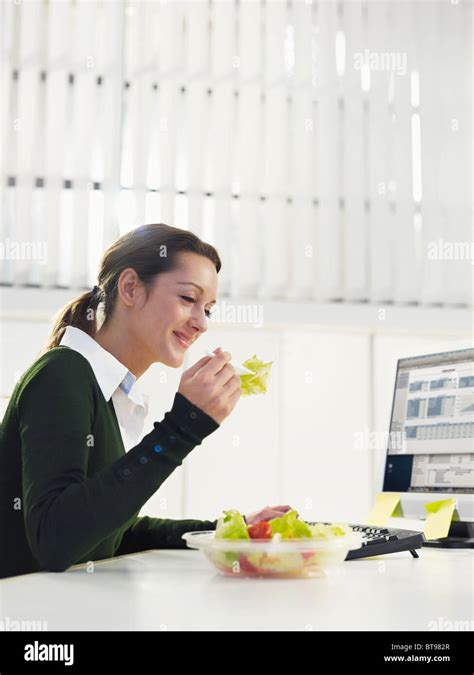 Businesswoman Eating Salad In Office Stock Photo Alamy