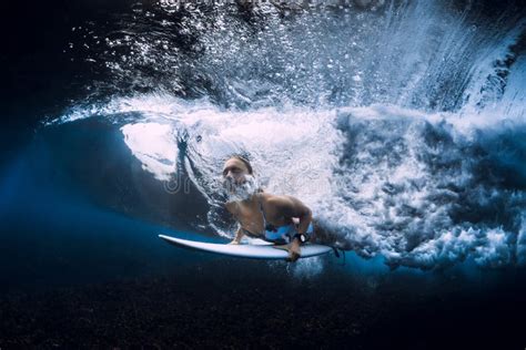 Surfer Girl With Surfboard Duck Dive Underwater With Wave Stock Photo