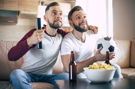 dois melhores amigos e fãs de futebol assistindo a algum jogo esportivo na tv e bebendo cerveja