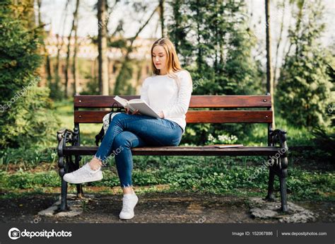 The Student Girl Sitting On A Bench Reading A Book In Park Stock Photo