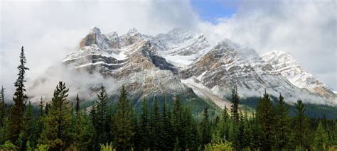 High Mountains Of The Canadian Rockies Surrounded By Clouds Along The