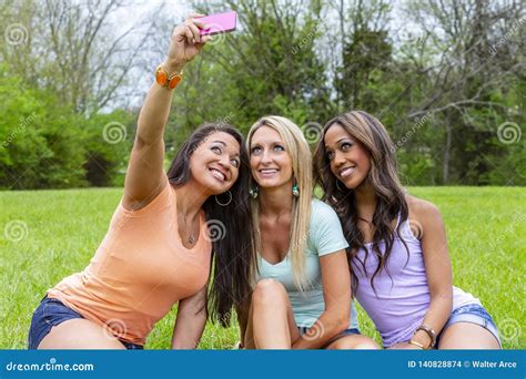 3 Girlfriends Enjoying A Day At The Park While Taking Selfies Stock