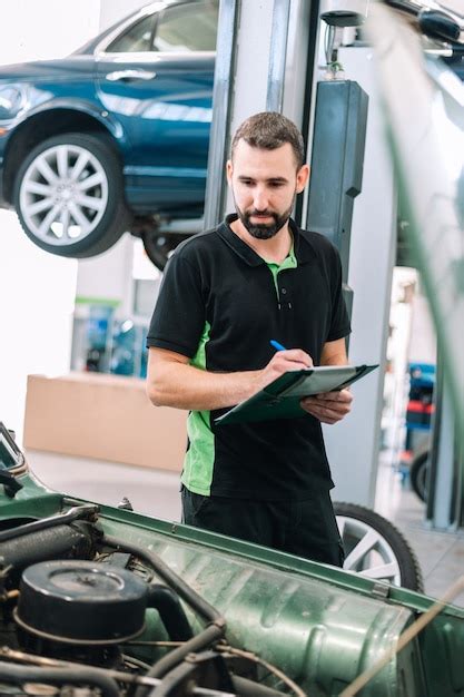 Premium Photo Car Mechanic Holding Clipboard And Checking To