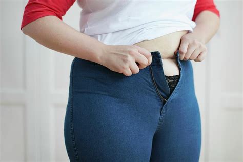 Woman Trying To Button Jeans Over Tummy Photograph By Science Photo Library