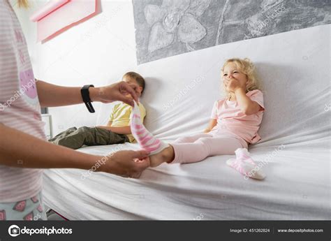 Mom Takes Off Her Little Daughters Socks And Tickles Her Feet A Little The Girl Laughs Stock