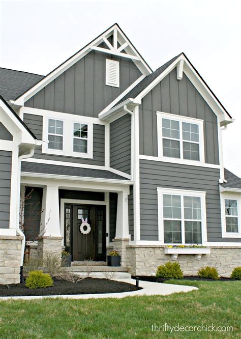 A Gray House With White Trim On The Front Door And Two Story Windows Is