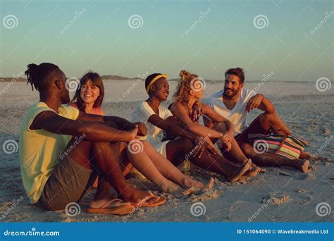 Friends Sitting Together On The Beach During Sunset Stock Photo Image