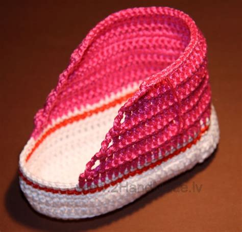 A Crocheted Pink And White Slipper Sitting On Top Of A Brown Table