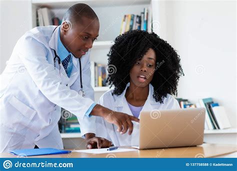 African American Male Doctor And Nurse Talking About Patient Stock
