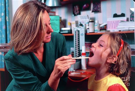 Doctor Checking Girls Throat For Tonsillitis Photograph By Mark Clarke
