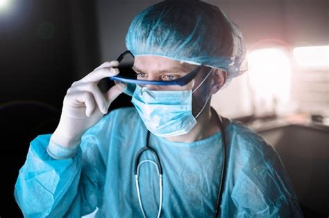 premium photo a doctor in a uniform and a mask with glasses works in a hospital late at night