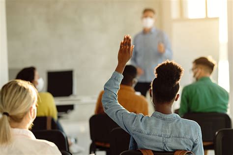 Rear View Of African American Student Raising Hand During A Class In