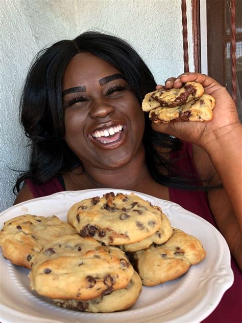 A Woman Is Holding Up Some Cookies On A Plate With Her Mouth Open And Smiling