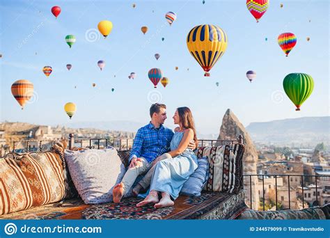 Happy Young Couple During Sunrise Watching Hot Air Balloons In