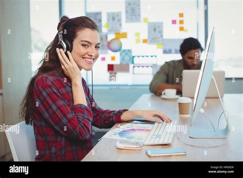 Female Graphic Designer Working While Listening Music In Office Stock