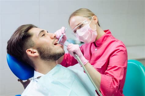 Professional Teeth Cleaning Dentist Cleans The Teeth Of A Male Patient