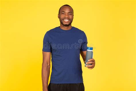 Fit Black Guy Holding Fitness Bottle Standing Over Yellow Background