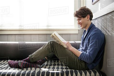 Young Man Reading Book On Sofa Stock Photo Dissolve