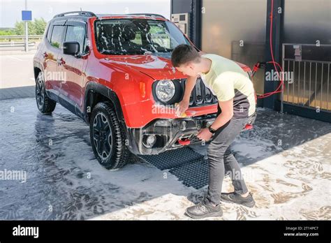A teenager washes a car with soap at a car wash. Manual car wash Stock