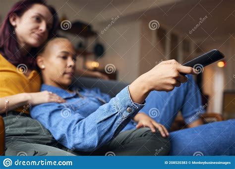 Loving Same Sex Female Couple Lying On Sofa At Home Watching Tv And Relaxing Together Stock