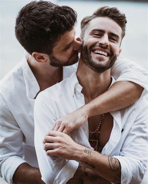 Two Men Are Embracing Each Other While One Is Wearing A White Shirt And The Other Has His Arm