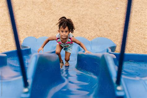 A Little Girl Climbing Up The Slide At The Playground By Stocksy