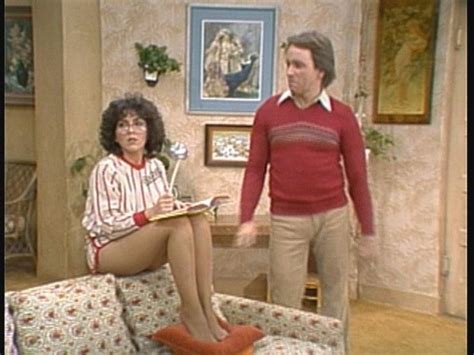 A Woman Sitting On Top Of A Couch Next To A Man In A Red Sweater