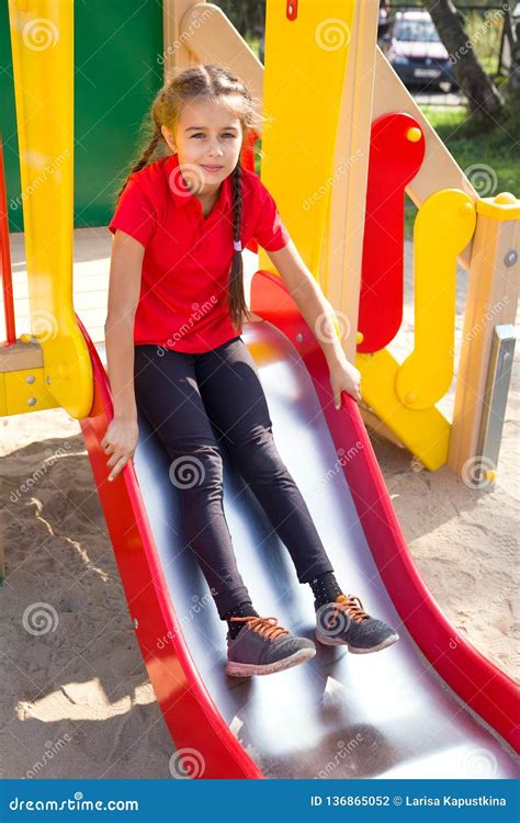 Cute Girl Playing On Playground Having Fun On A Slide Stock Photo