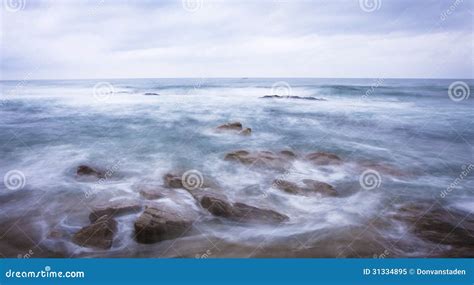 Dark Rocks In A Blue Ocean Under Cloudy Sky Stock Image Image Of