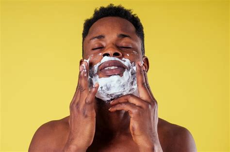그의 얼굴에 면도기와 면도 거품을 가진 아프리카계 미국인 남자 프리미엄 사진