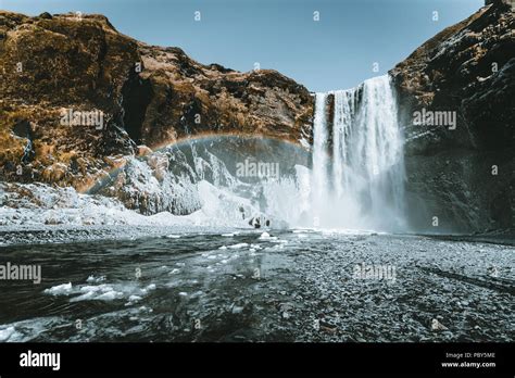 Skogafoss Waterfall In Iceland With Rainbow On A Sunny Day With Blue