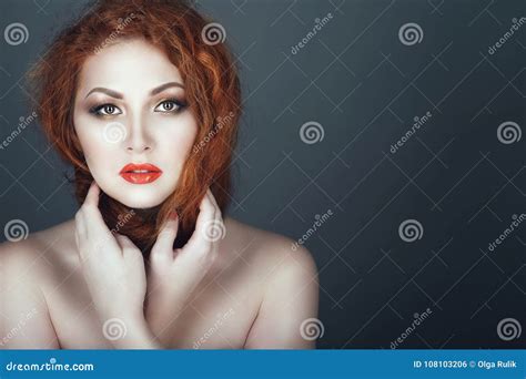 Gorgeous Red Headed Woman With Beautiful Make Up And Naked Shoulders Winding Her Hair Around Her