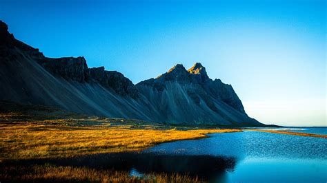 Grass Covered Lake Near White Covered Mountain Under Blue