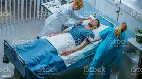 Emergency In The Hospital Doctor And Nurse Rush To Safe Dying Patient Man Is Lying On The Bed
