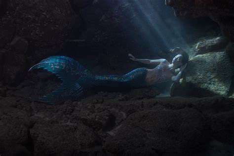 A Woman Is Laying On The Rocks Under Water