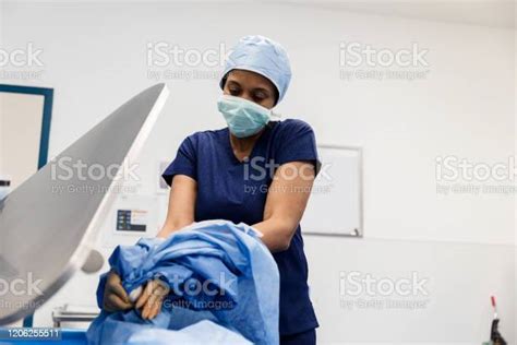Mature Female Surgeon Taking Off Surgical Gown Stock Photo Download