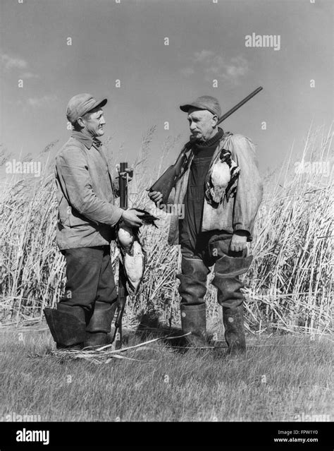 1940s Two Men Duck Hunting Standing In Marsh Grass Talking Holding