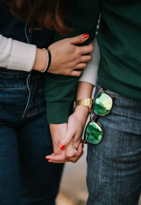 A Couple Wearing Green Shirts And Jeans Holding Hands Couple Holding
